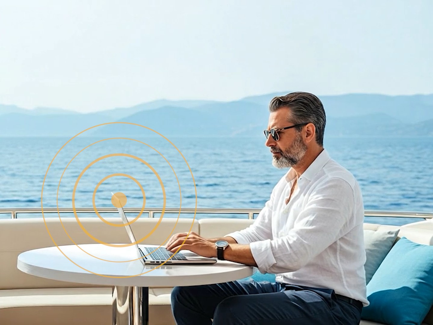 A man on a superyacht looks at a laptop connected to the internet by satellite network