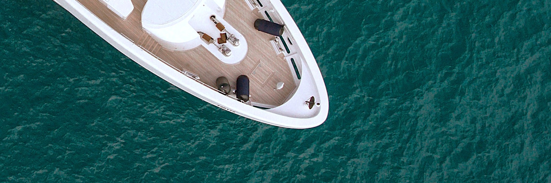 An overhead view of a superyacht bow in murky waters