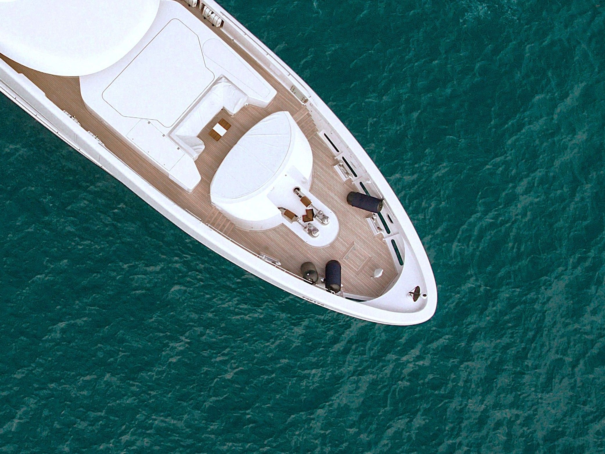 An overhead view of a superyacht bow in murky waters