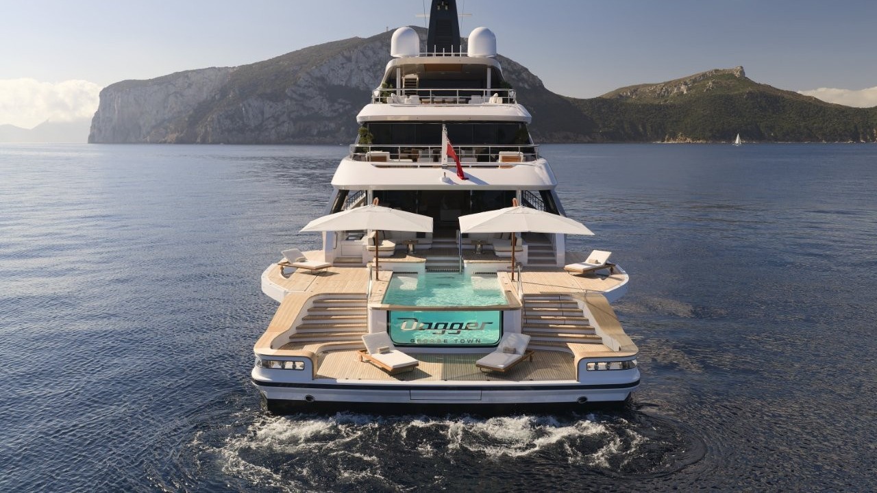 A view of a white, sleek superyacht cruising at speed on a sunny day