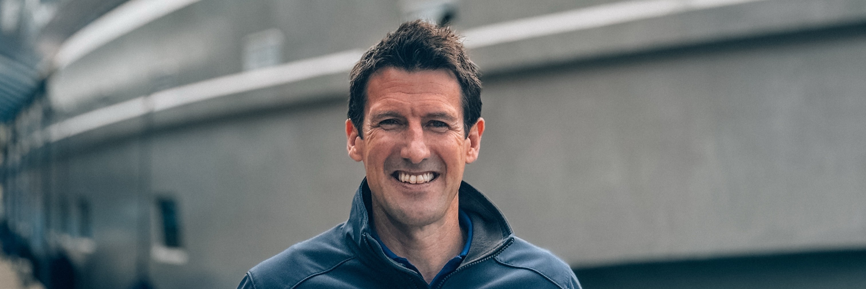 A profile photo of Tom Humphreys standing in front of a docked yacht