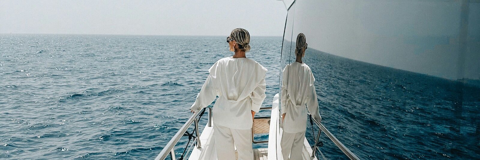A women stands at the side deck of a superyacht gazing at the horizon