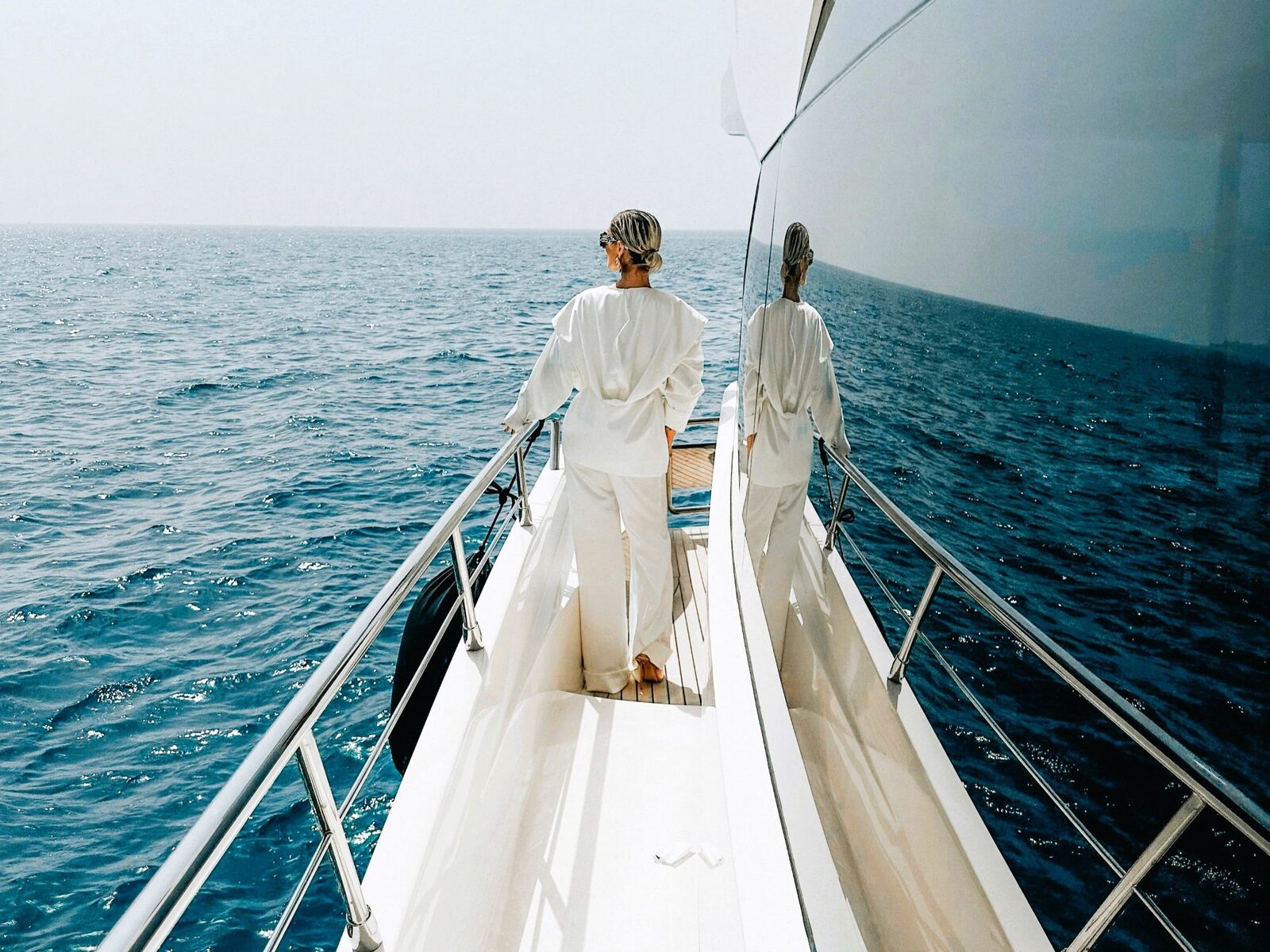 A women stands at the side deck of a superyacht gazing at the horizon